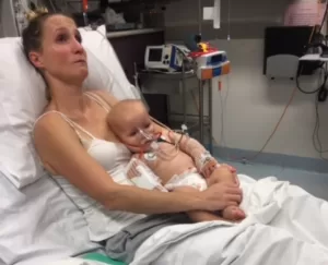 Mother holding baby with meningitis, in hospital.